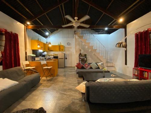 a living room with couches and a ceiling fan at Big Fun Beach House in Bacong