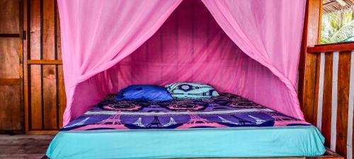a bed in a tent with a pink canopy at Nyanderos homestay in Poelau Mansoear