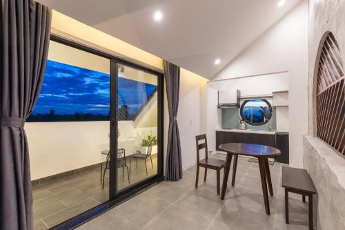 uma sala de jantar com uma mesa e uma grande janela em Anchie Retreat Villa Hội An em An Bàn (2)