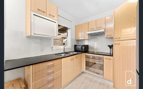 a kitchen with wooden cabinets and a black counter top at The Illawarra Hideaway - Close to everything!