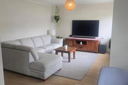 a living room with a couch and a flat screen tv at The Illawarra Hideaway - Close to everything!