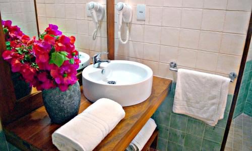 a bathroom with a sink and a vase of flowers at Iara Beach Hotel Boutique in Salvador