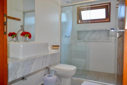 a bathroom with a toilet and a glass shower at Casa Marah - Trancoso in Trancoso