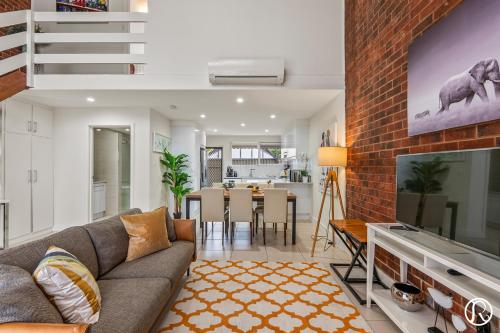 a living room with a couch and a brick wall at Norwood Urban Sanctuary Condo 2b1b free parking in Norwood
