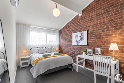 a bedroom with a bed and a brick wall at Norwood Urban Sanctuary Condo 2b1b free parking in Norwood