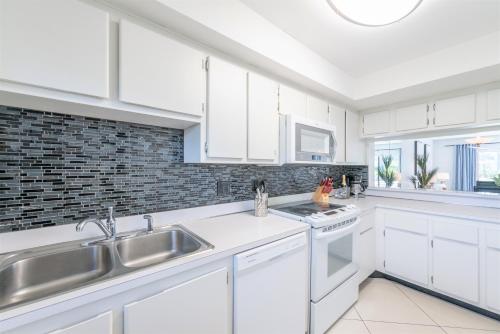 een witte keuken met witte kasten en een spoelbak bij Canaveral Towers 401 in Cape Canaveral
