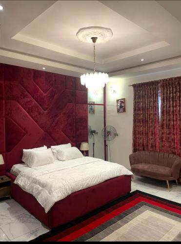a bedroom with a large bed with a red wall at AlphaDreams Villa in Magodo