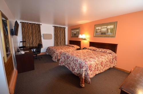 a hotel room with two beds and a desk at Williamstown Motel in Williamstown