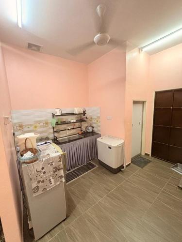 a room with pink walls and a kitchen with appliances at Saaidah Homestay in Pendang