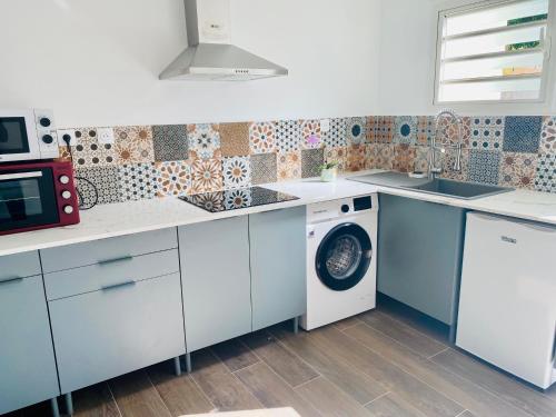 a kitchen with a washing machine and a microwave at Letoilevelli in Salazie