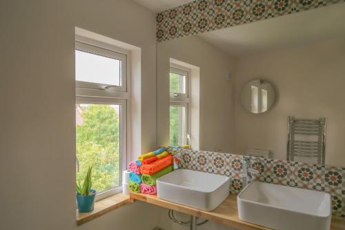 4 bedroom home - N17 في لندن: مغسلتين بيضاء في حمام مع نافذة