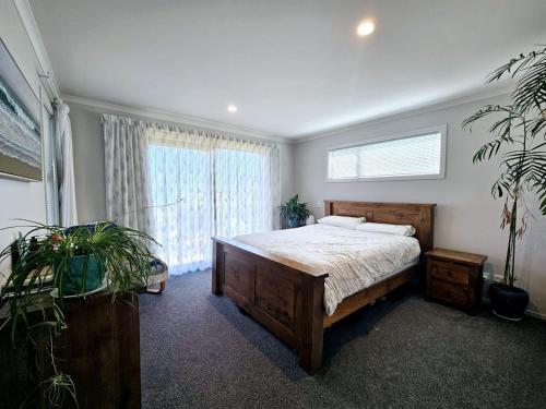 ein Schlafzimmer mit einem Bett und einem großen Fenster in der Unterkunft Pōhutukawa House Pohara in Pohara