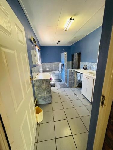 a kitchen with blue walls and a white tile floor at Biba's Rooms in Smithfield