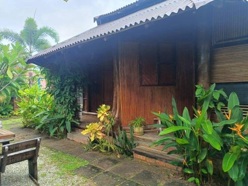 a wooden house with a bench in front of it at Cahaya Wooden Studio in Pantai Cenang