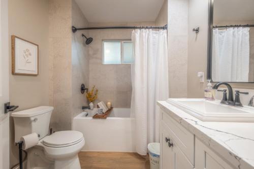 a white bathroom with a toilet and a sink at Folsom Old Town Escape in Folsom