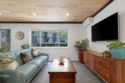 a living room with a blue couch and a flat screen tv at Renovated Beach Escape in Surfers, Surf at Your Door, Cavill a Short Stroll in Gold Coast