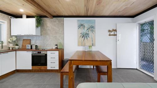 a kitchen with white cabinets and a wooden table at Renovated Beach Escape in Surfers, Surf at Your Door, Cavill a Short Stroll in Gold Coast