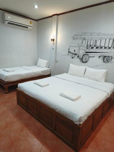 two beds in a room with a drawing on the wall at Old City Guest House in Sukhothai