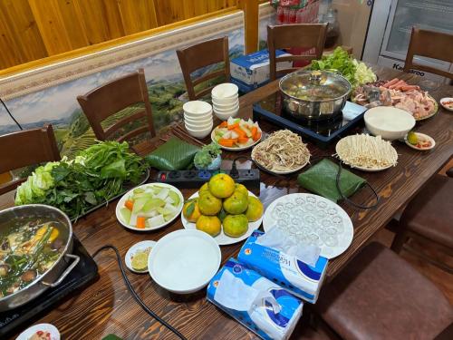 a wooden table topped with plates of food and vegetables at Sen Sapa Retreat & Tours in Sa Pa