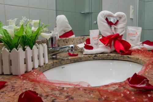 a bathroom sink with towels and flowers in a mirror at Marsallis Praia Hotel in Natal