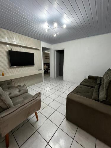 a living room with a couch and a flat screen tv at Casa no centro de Torres in Torres