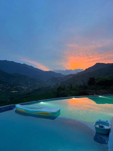 a swimming pool with a sunset in the background at O Châu Homestay Lào Cai in Lao Cai