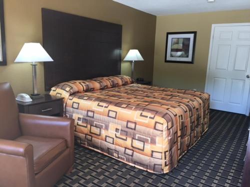 a hotel room with a bed and a chair at Executive Inn and Suites Longview in Longview