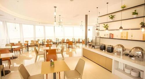 un restaurant avec des tables et des chaises dans une salle dans l'établissement City Comfort Inn Nantong Qidong Renmin Zhong Road Xingfudao, à Huilongzhen