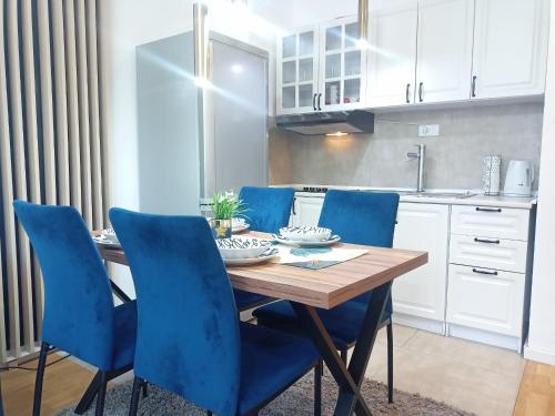 eine Küche mit einem Holztisch und blauen Stühlen in der Unterkunft Magnolia Lux Apartments in Sokobanja