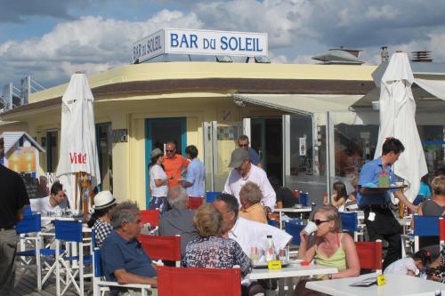 un grupo de personas sentadas en las mesas frente a un restaurante en Un Homme Et Une Femme, en Deauville