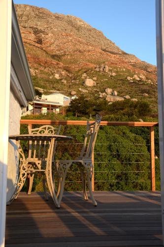 a table and chairs sitting on a porch with a hill at Rocklands Seaside Bed and Breakfast in Simonʼs Town