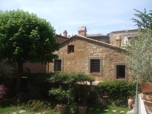 una vecchia casa in pietra con un albero nel cortile di Feronia - Le Dimore di Borgo Tessile a Orvieto