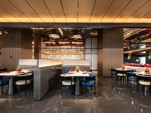 Un comedor con mesas y sillas en un restaurante. en Radisson RED Wuhan Jianghan Road Pedestrian Street Riverside, en Wuhan