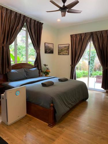 a bedroom with a large bed with a ceiling fan at Highlanders Garden Guesthouse at Arundina Cameron Highlands in Cameron Highlands