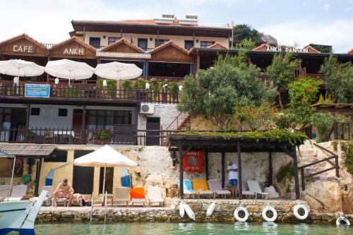 Un hotel sobre el agua con sillas y sombrillas. en Ankh Pension, en Kaleucagız