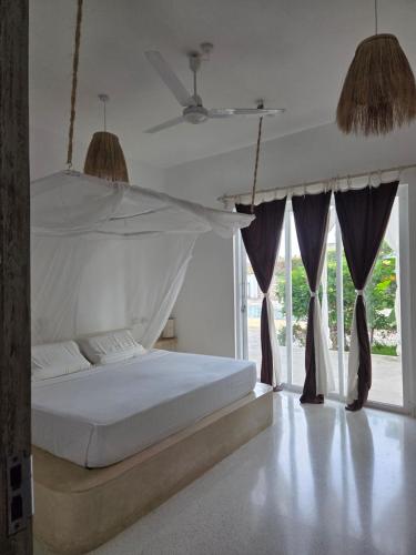 Un dormitorio con una cama blanca con dosel. en Kupenda House - Milele Resort Tamu, Watamu, en Watamu