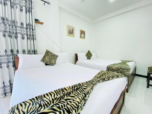 Dos camas en una habitación con paredes blancas. en Hikka Heaven Guest House, en Hikkaduwa