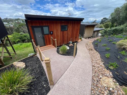 a small wooden cabin with a walkway at Hidden Valley Waiheke in Palm Beach