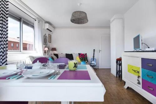 eine Küche und ein Wohnzimmer mit einem Tisch mit Tellern darauf in der Unterkunft Le Clos Des Violettes in Toulouse