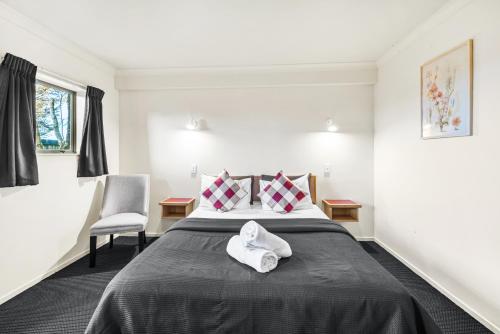 a bedroom with a bed and a chair at New Castle Motor Lodge in Rotorua