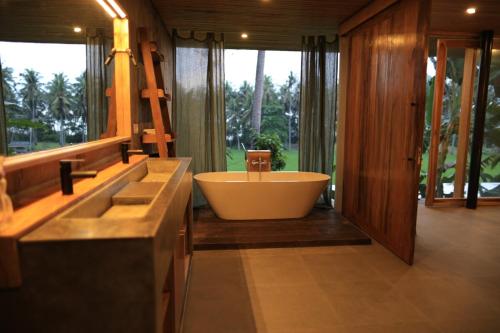 Un baño grande con bañera y una ventana grande en Soma Beach House, en Balian