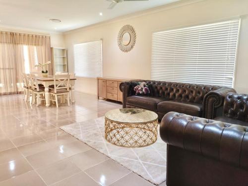 Una sala de estar con un sofá de cuero y una mesa. en underwood MyHill, en Kuraby