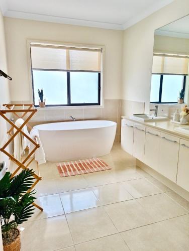 a bathroom with a large tub and a sink at Modern Retreat by Underwood market&51 Area in Kuraby