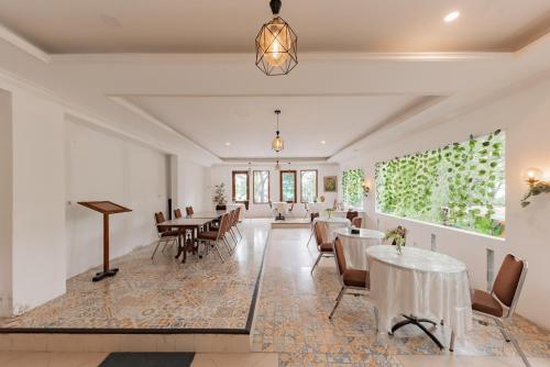 a dining room with tables and chairs and windows at Urbanview De Ethnic Hotel Bandung by RedDoorz in Bandung