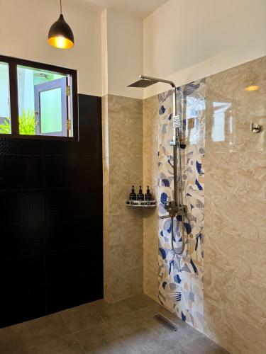 a bathroom with a shower with blue and white tiles at Lum Residence in Ahangama
