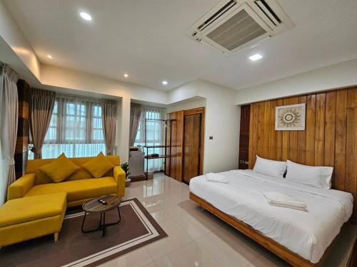 a bedroom with a large bed and a yellow couch at Madugu Service Apartment in Chiang Mai