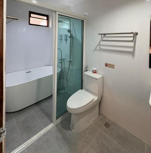 a bathroom with a toilet and a glass shower at Proud Chiang Mai Poshtel in Chiang Mai