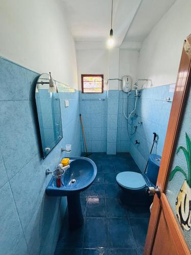 a blue bathroom with a sink and a toilet at Nimsara Lodge in Hikkaduwa