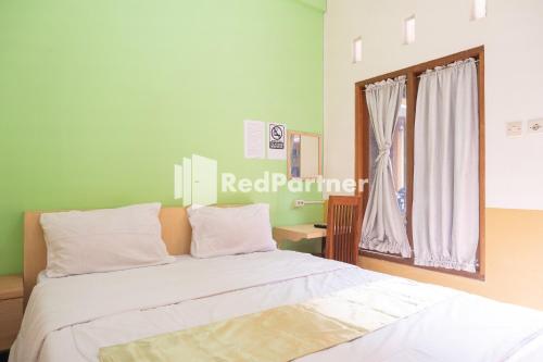 a bedroom with a bed with white sheets and a window at Wisma Handayani Syariah RedPartner near RSUD Wonosari in Yogyakarta
