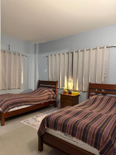 une chambre avec deux lits et une fenêtre avec des rideaux dans l'établissement Mon Jam Cottage, à Chiang Mai